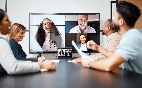 Staying connected with colleagues around the world. a diverse group of businesspeople sitting in the boardroom during a meeting with their international colleagues via video chat