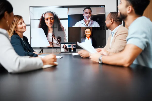 A meeting across international boarders. a diverse group of businesspeople sitting in the boardroom during a meeting with their international colleagues via video chat