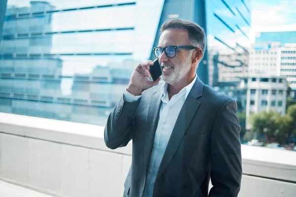 Go-getters get things done. a mature businessman using a phone in front of a building in the city