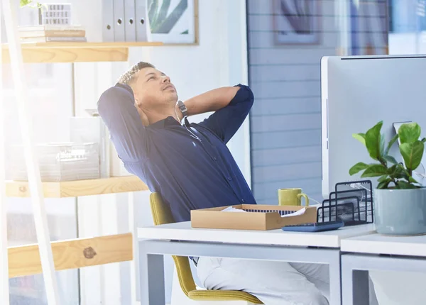 I feel relieved now that this project is out of the way. a businessman looking relaxed while sitting at his desk