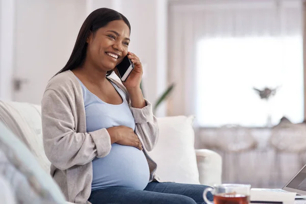 The baby gets excited every time you call. a pregnant woman talking on her cellphone while sitting on the sofa at home