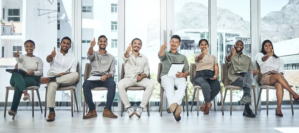 Do you love your job. a group of people showing thumbs up in a modern office