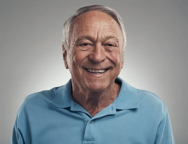 It feels good to smile again. a man happily smiling at the camera in a studio against a grey background