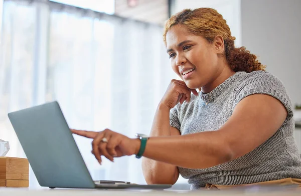 Confused businesswoman reading an email on a laptop indoors. One young corporate professional looking at confusing analytics data with unsure expression while doing social media seo website analysis.