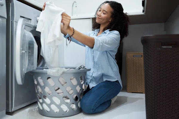 This washing powder really makes clothes sparkle. a young woman preparing to wash a load of laundry at home