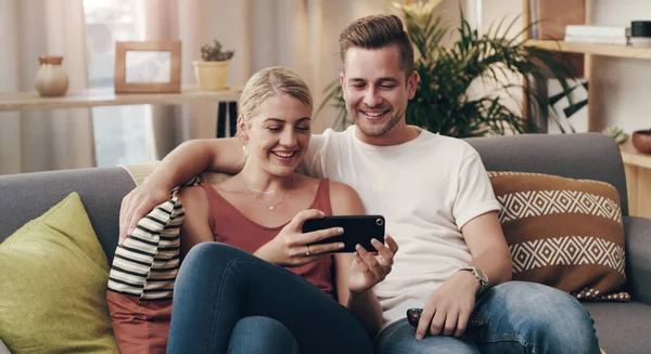 You make me feel safe and loved. a young couple using a smartphone on the sofa