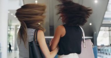 Fun, carefree and laughing women doing shopping, retail therapy and spending time together at the mall. Two young and stylish best friends, beauty shopper or customers looking back with a hair flip.