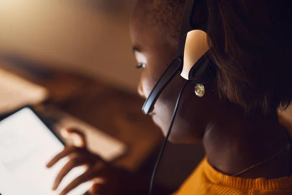 Young student browsing, learning online and searching the web at night on a tablet. Woman watching educational videos with headset, reading from the internet and participating in an online class.