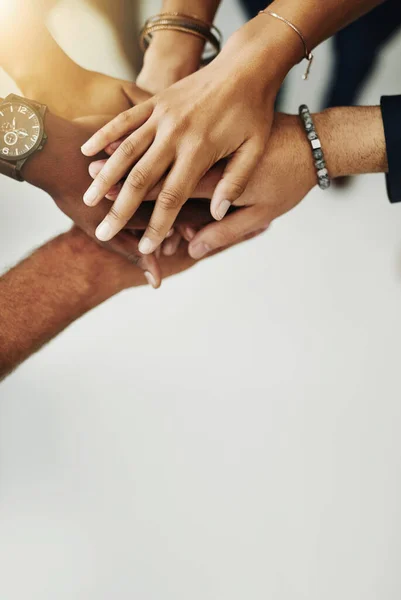 Hands in a huddle for teamwork, unity and working together from above. Closeup of a diverse group or team collaborating, joining and connected as a united people, showing solidarity and cooperation.
