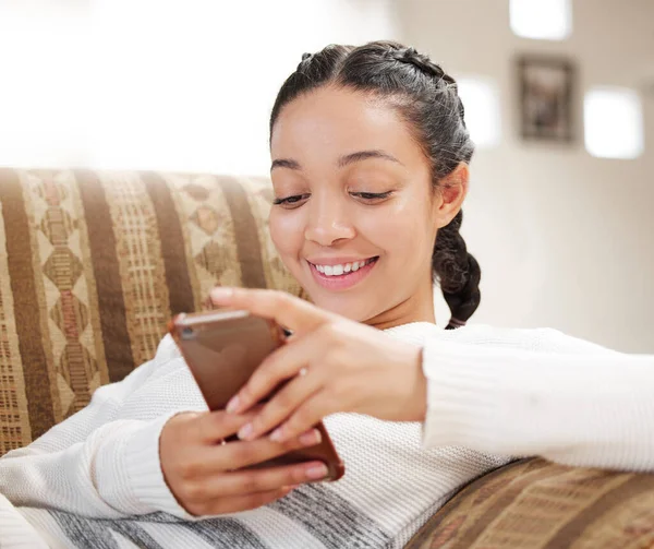 Social media is the new hangout spot. a young woman using a smartphone on the sofa at home
