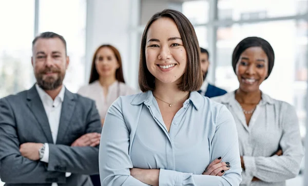 Teamwork strengthens self-growth too. Portrait of a businesswoman standing in an office with her colleagues in the background