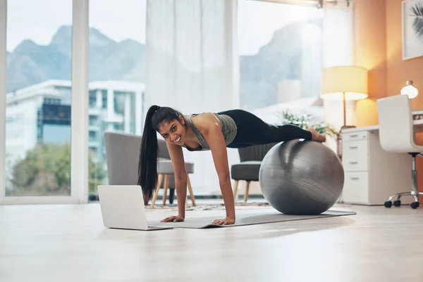 You dont need the gym when you have the internet. a woman working out in her living room with her laptop in front of her