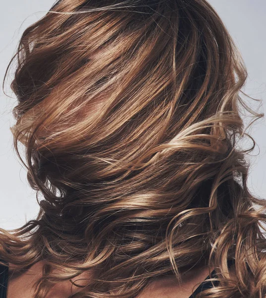 Gorgeous hair is the best revenge. a womans hair covering her face while posing against a grey background