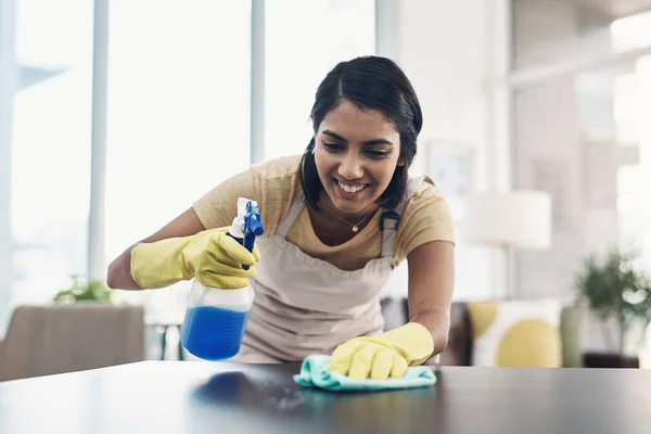 A clean home is a safe home. a young woman disinfecting a table at home