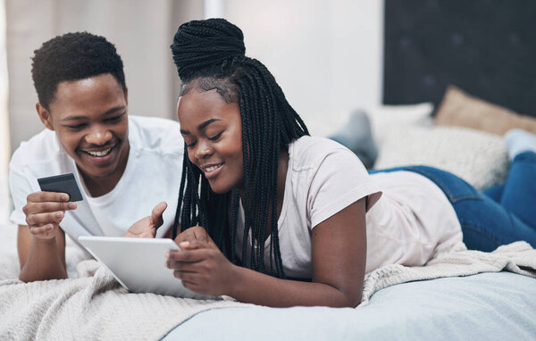 Quarantine doesnt have to be inconvenient thanks to credit. a young couple using a digital tablet and credit card while relaxing on their bed at home