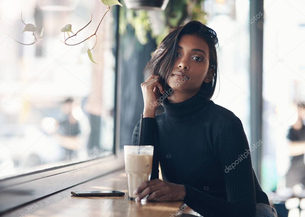 Dont just be plain coffee, be iced coffee. a beautiful young woman drinking a iced coffee in a cafe