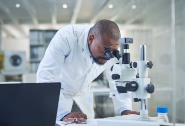 The master of medical research himself. a scientist using a microscope while conducting research in a laboratory