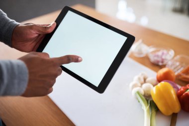 You can cook like a pro if you have the right resources. an unrecognizable man using a digital tablet while cooking at home