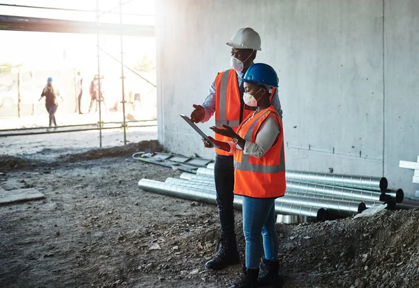 Profitable relationships are built on a foundation of trust. a young man and woman having a discussion while working at a construction site