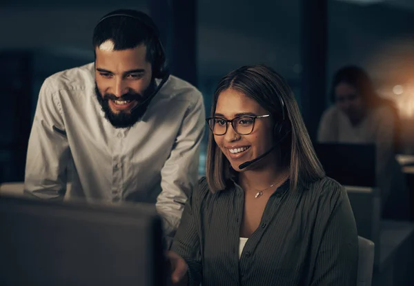 Working the late nights with big smiles on their faces. two call centre agents working together in an office at night