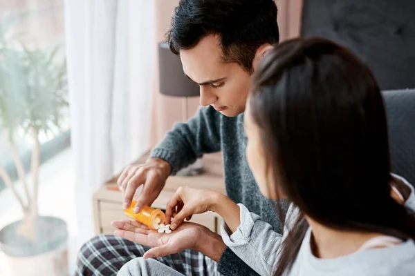 Caring is sharing, except when youve got the flu. a young couple taking medication while recovering from an illness in bed at home