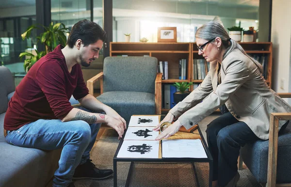 An ink pattern that determines your thought pattern. a mature psychologist conducting an inkblot test with her patient during a therapeutic session