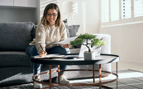 Success is in the little things you do. a young woman looking at paperwork while working from home