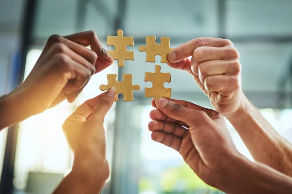 Group of business people holding puzzle pieces. Professionals connect and collaborate together inside office building. Closeup of hands, and team working together on a new strategy for success.