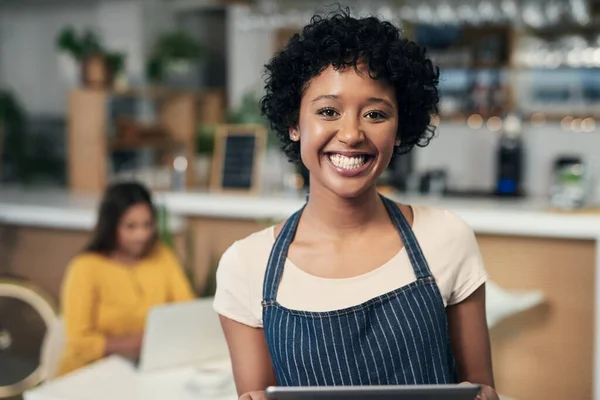 Technology helps business owners remain organised. Portrait of a young woman using a digital tablet while working in a cafe