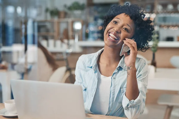 It feels good when your hard work starts to pay off. a businesswoman talking on her cellphone while working from a cafe