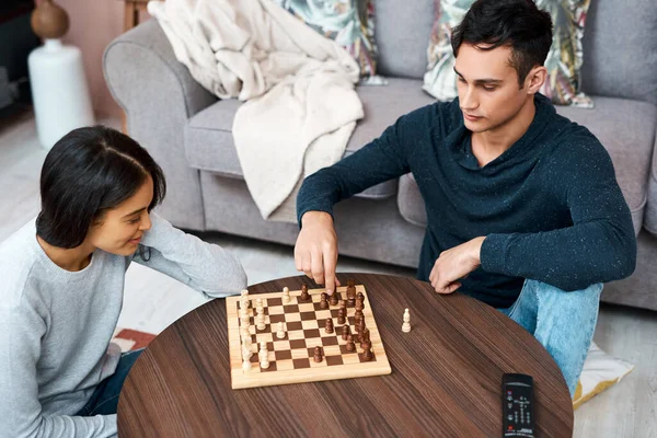 How is your lockdown going to play out. a young couple playing a game of chess at home