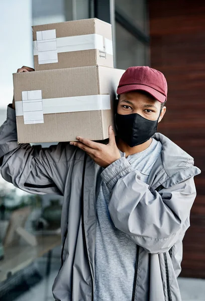 Keeping customers happy at a safe distance. a masked young man delivering a package to a place of residence