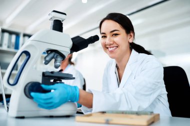 Scientific research is indispensable to informing the future of healthcare. Portrait of a young scientist using a microscope in a lab