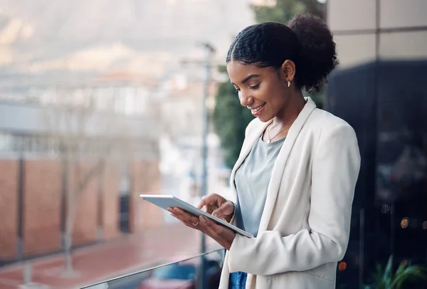 Modern business woman on a tablet during a work break alone outside. Smiling corporate worker looking at web and social media posts on a balcony. Female employee on a digital device with copyspace.