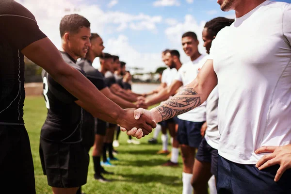 Play well, play fair. a group of young rugby players shaking hands on the field