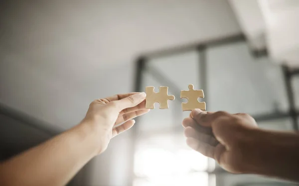 Closeup hands of partners in unity, planning and working on strategy puzzle piece game. People collaborating on innovative jigsaw parts to fit together as part of teamwork planning project