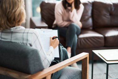 Keep talking until the answers become clearer. a psychologist writing notes during a therapeutic session with her patient clipart