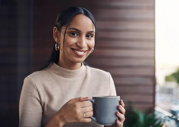 Whats a work day without coffee. Cropped portrait of an attractive young businesswoman drinking her coffee while working in the office