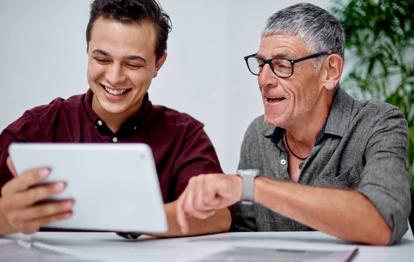 This app has been quite handy for us. two businessmen working together on a digital tablet in an office