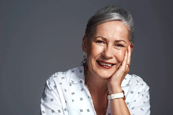 I have so many good stories to tell. Studio shot of a senior woman posing against a grey background