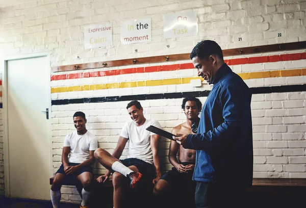 Well guys, lets say I have good news for you. a rugby coach addressing his team players in a locker room during the day