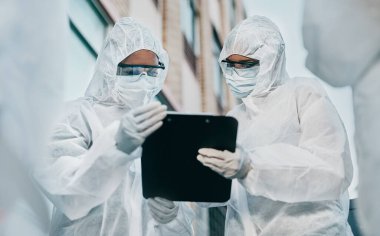 Hazmat wearing doctor and nurse working as a medical team and healthcare professionals at a quarantine site. Health and safety colleagues in protective gear ready to fight a virus or pandemic.