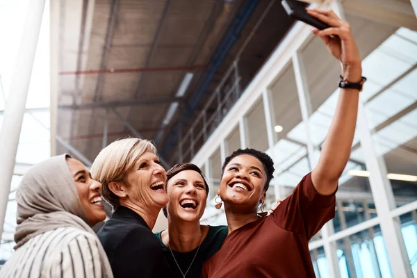 You can just tell that they have the utmost confidence. Portrait of a group of businesswomen taking selfies together in an office