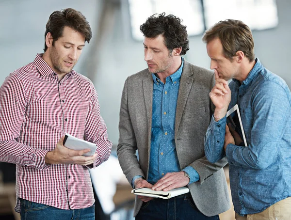 Designs from paper to digital. Shot of a group of male coworkers taking over a digital tablet in an office