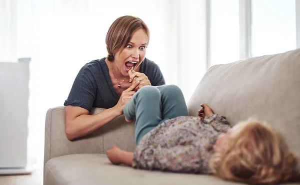 Im going to eat your toes. an attractive young mother and playing with her daughter in the living room at home