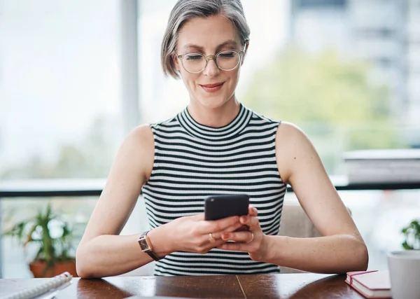 Social media helped me to be even more successful. a mature businesswoman using her cellphone while sitting at her desk