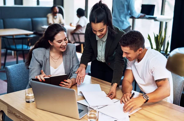 Its amazing what you can achieve as a dedicated team. a group of businesspeople going through paperwork together in an office