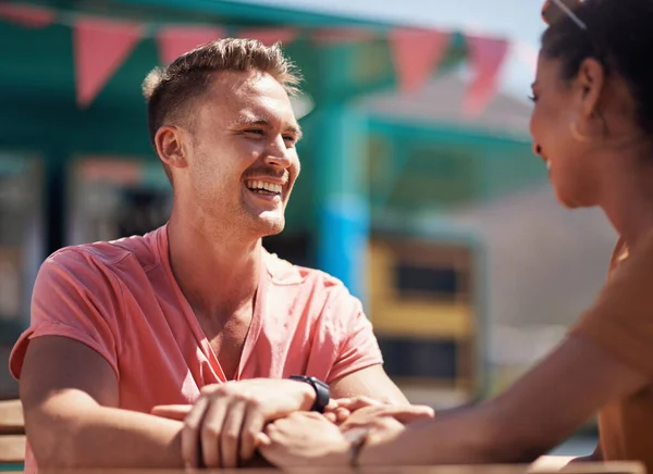 You know how to make me laugh. a cheerful young couple having a lunch date outside next to a beach promenade