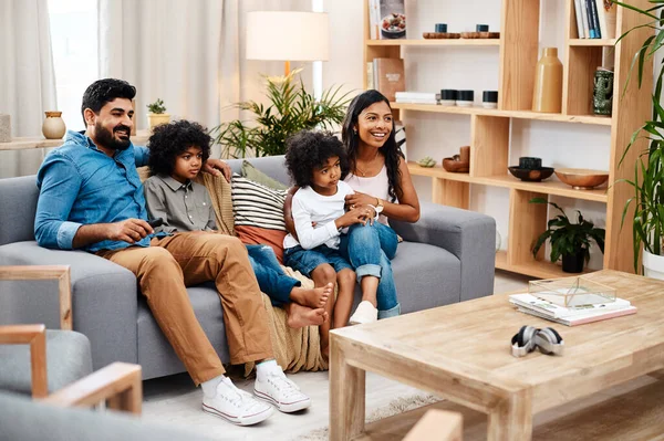 Watching movies is a family activity. Full length shot of a beautiful young family sitting on sofa and watching tv together at home