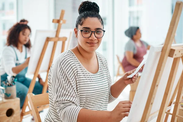 I am at my happiest when I am painting. Cropped portrait of an attractive young woman sitting with her friends and painting during an art class in the studio